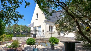 A house with a triangular roof, a stone pathway, and a garden with potted plants and a table. - Lovely house with garden, 8 adults and 2 children (Plobannalec-Lesconil)