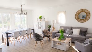 A modern living room with a grey sofa, a dining area with a table and chairs, a chandelier, and a large mirror on the wall. - Lovely house with garden, 8 adults and 2 children (Plobannalec-Lesconil)