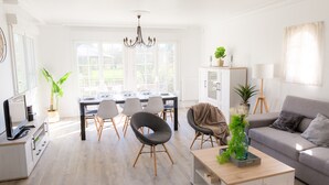 A bright, modern living room with a dining area, a grey sofa, and a chandelier. - Lovely house with garden, 8 adults and 2 children (Plobannalec-Lesconil)