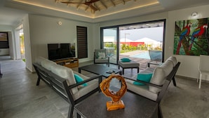 A modern living room with a TV, sofas, and a coffee table. - Sea View Villa with Pool & Hot Tub - Sleeps 8 (Saint-François)