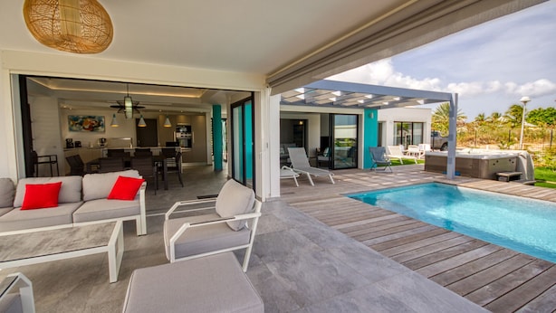 A modern outdoor living area with a pool, seating, and a covered patio. - Sea View Villa with Pool & Hot Tub - Sleeps 8 (Saint-François)