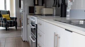 A modern kitchen with white cabinets, stainless steel appliances, and a tiled backsplash. - Stunning 3-bed Cottage in Lowestoft (Lowestoft)