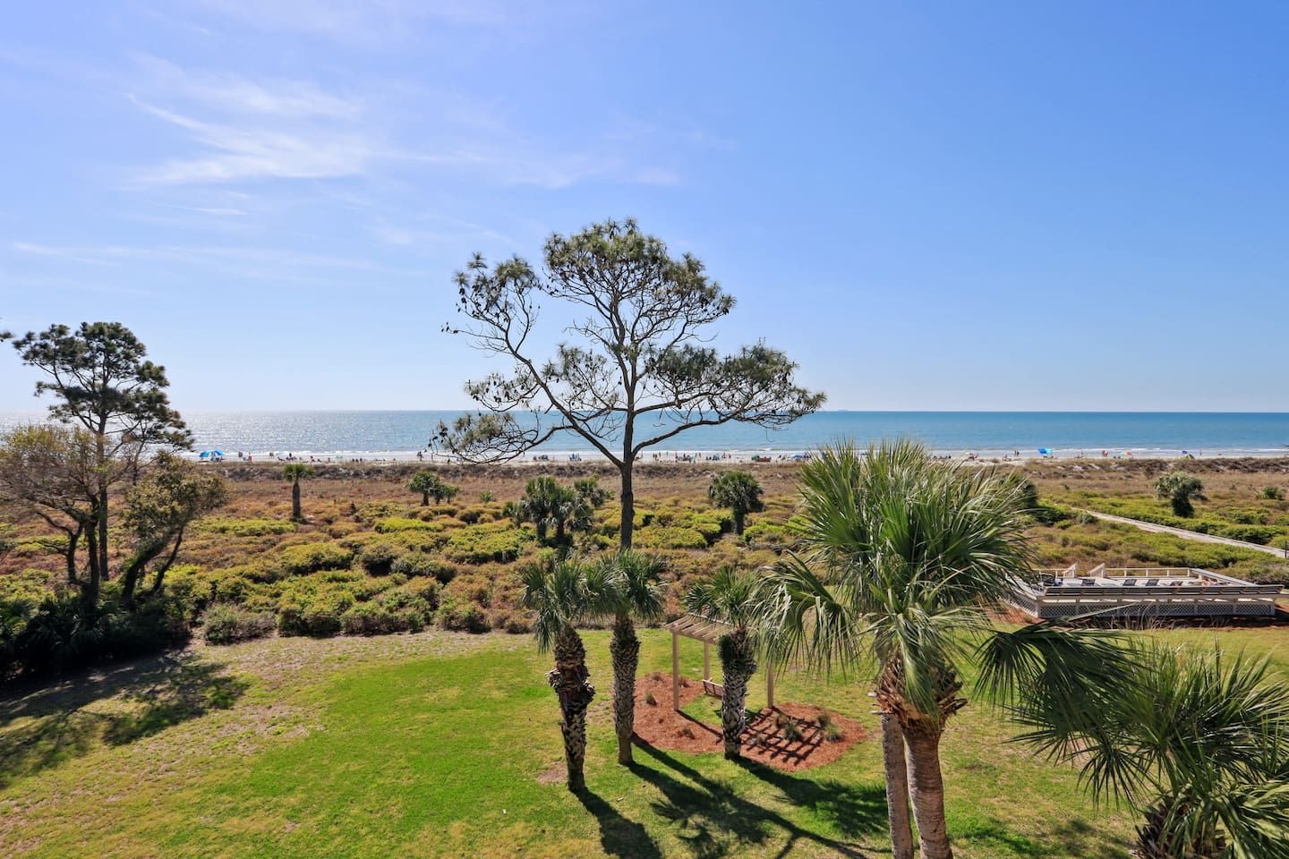 A coastal landscape with a beach, trees, and a building with a roof.