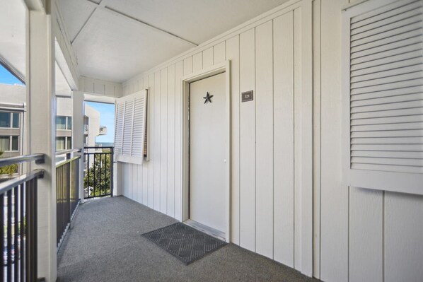 A hotel corridor with a door marked with a star, a number plate, and a window with blinds.