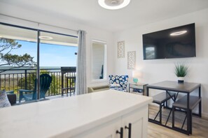 Enjoy a spacious room with a large TV, balcony, and seating area offering a view of the outdoors.