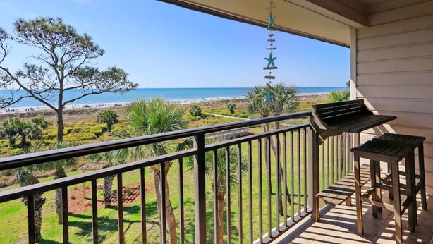 Varanda com vista para a praia, um adorno de estrela pendurada e uma mesa pequena.