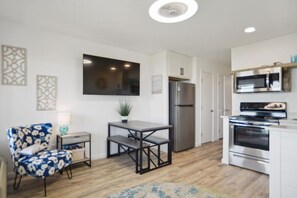 A modern kitchen with a refrigerator, oven, microwave, and dining area with a table and chairs.