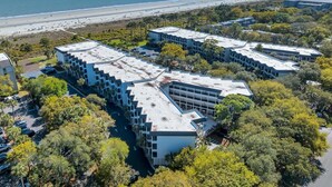 A modern hotel with a rooftop pool, surrounded by lush greenery and a beach view. - Unmatched Views at Seaside Villa  Steps to the Sand (Hilton Head Island)