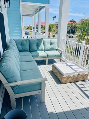 Relax in a serene outdoor space with a comfortable sofa and ottoman, surrounded by lush palm trees.