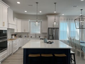 Enjoy cooking in this well-lit kitchen with sleek cabinetry, a large island, and a stainless steel refrigerator.