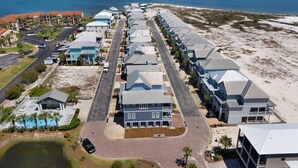 Een hotel aan het strand met een rij kamers met uitzicht op de oceaan, een parkeerplaats en een zwembad.