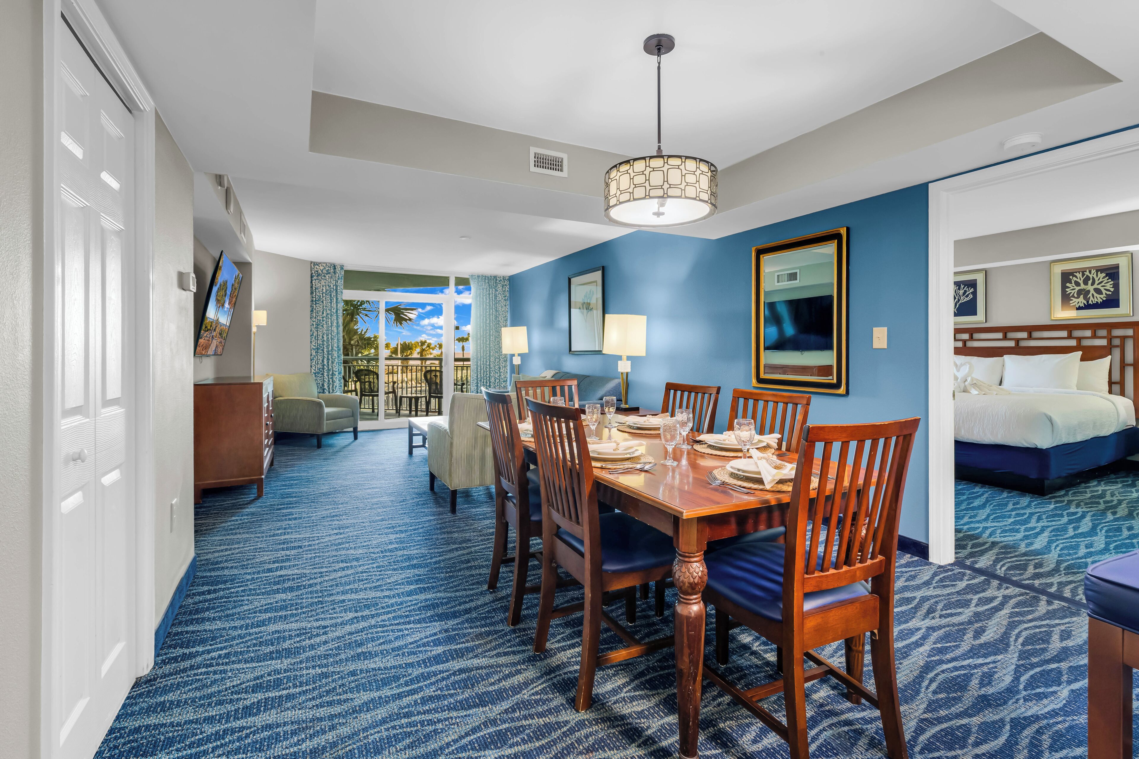 A hotel room with a dining area, a bed, and a view of the outdoors.