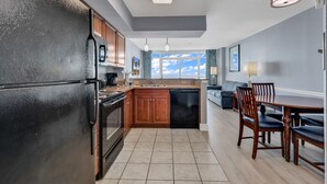 A modern kitchen with a black refrigerator, wooden cabinets, and a dining area with a table and chairs. - Dunes Village Resort by Hosteeva (Myrtle Beach)