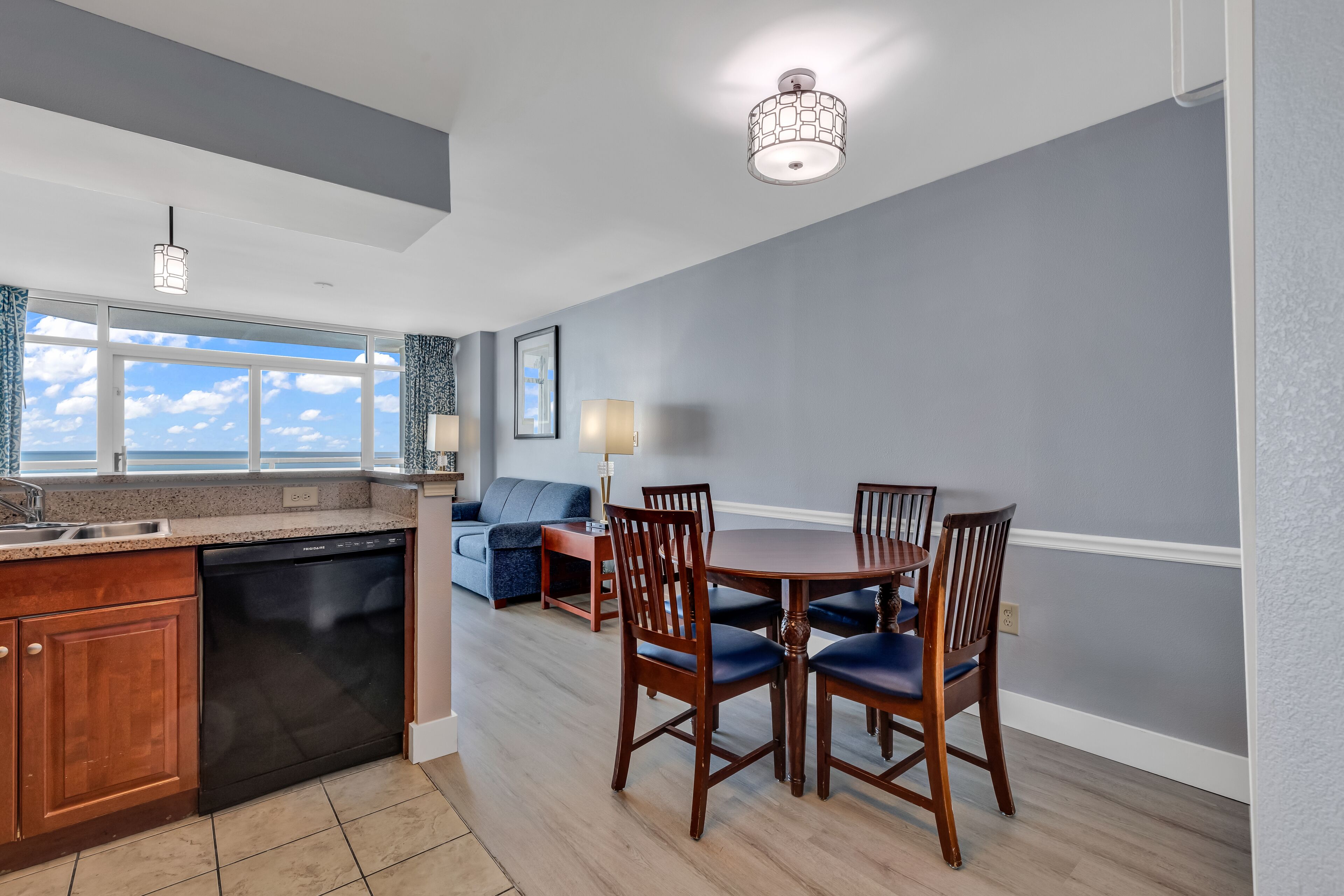 A modern kitchen with a dishwasher, wooden cabinets, and a dining area with a table and chairs.
