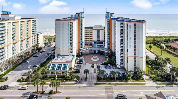 A high-rise hotel with multiple floors, a central courtyard, and a view of the beach. - Dunes Village Resort by Hosteeva (Myrtle Beach)