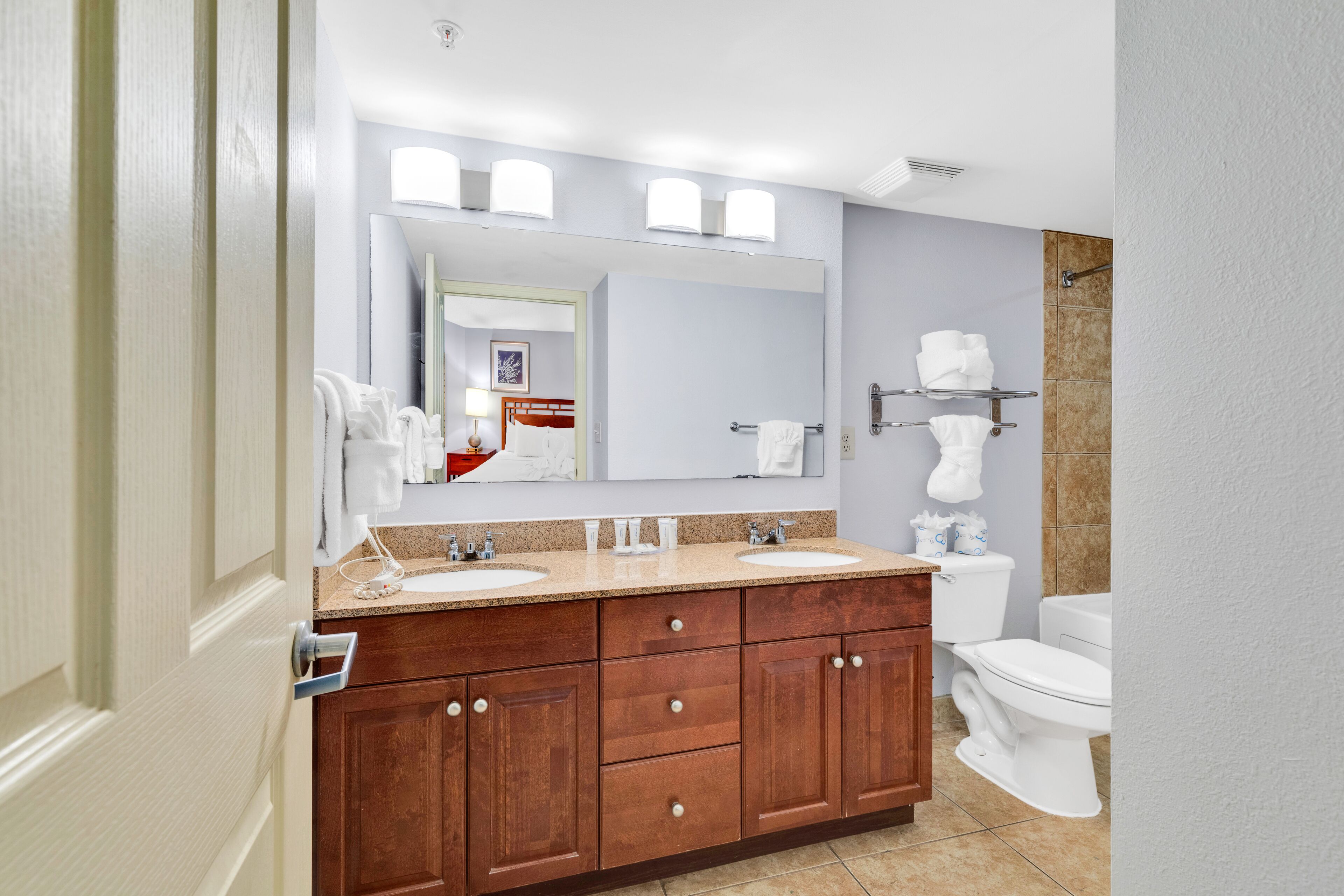 A bathroom with two sinks, a large mirror, and a toilet.