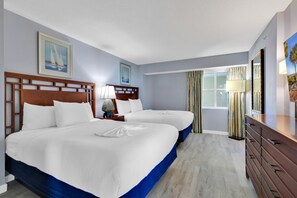 A hotel room with two beds, a wooden headboard, a dresser, a lamp, and a window with curtains. - Dunes Village Resort by Hosteeva (Myrtle Beach)