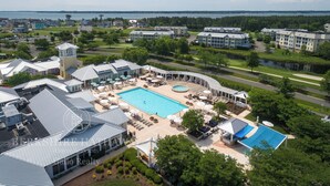 A residential complex with a swimming pool, outdoor seating, and a view of the water body.