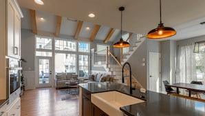 A spacious kitchen with wooden beams, a central island with a sink, and a dining area with a table and chairs.