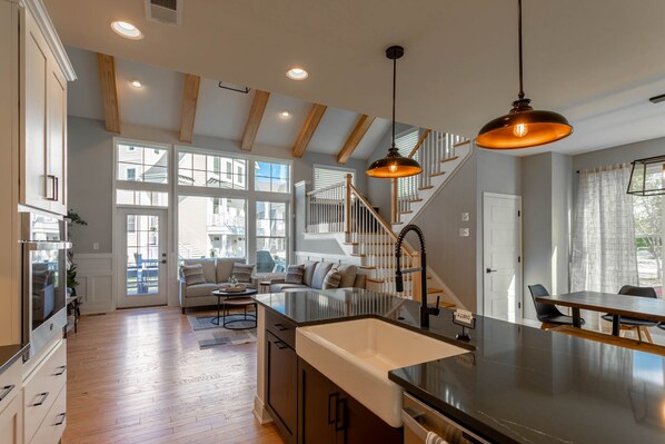 A spacious kitchen with wooden beams, a central island with a sink, and a dining area with a table and chairs.
