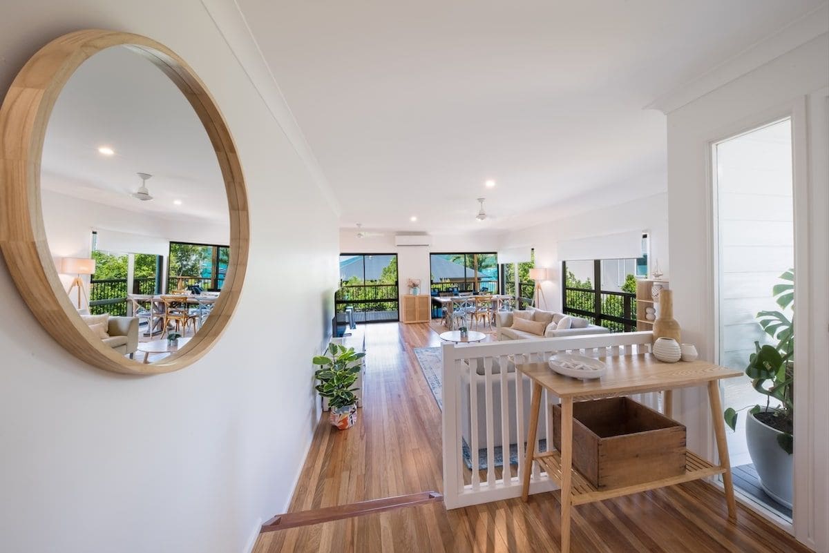 A spacious living area with a large mirror, wooden flooring, and a view of the outdoors.