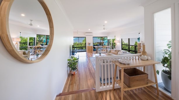 A spacious living area with a large mirror, wooden flooring, and a view of the outdoors. - Beach House on Main- Airlie Beach (Airlie Beach)