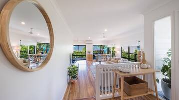 A spacious living area with a large mirror, wooden flooring, and a view of the outdoors.