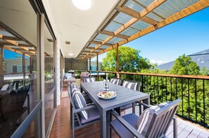 Ein Essbereich im Freien mit Tisch und Stühlen, einer Glasbrüstung und Blick auf Grünflächen und Gebäude.