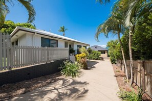 A single-story house with a white exterior, a picket fence, and a paved driveway. - Beach House on Main- Airlie Beach (Airlie Beach)