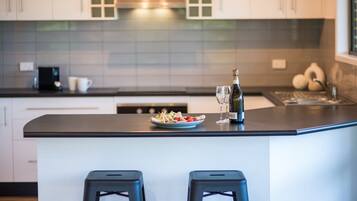 A modern kitchen with a central island, bar stools, and a bottle of champagne.