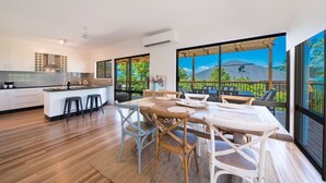 A modern kitchen with a large island, bar stools, and a dining area with a wooden table and chairs.