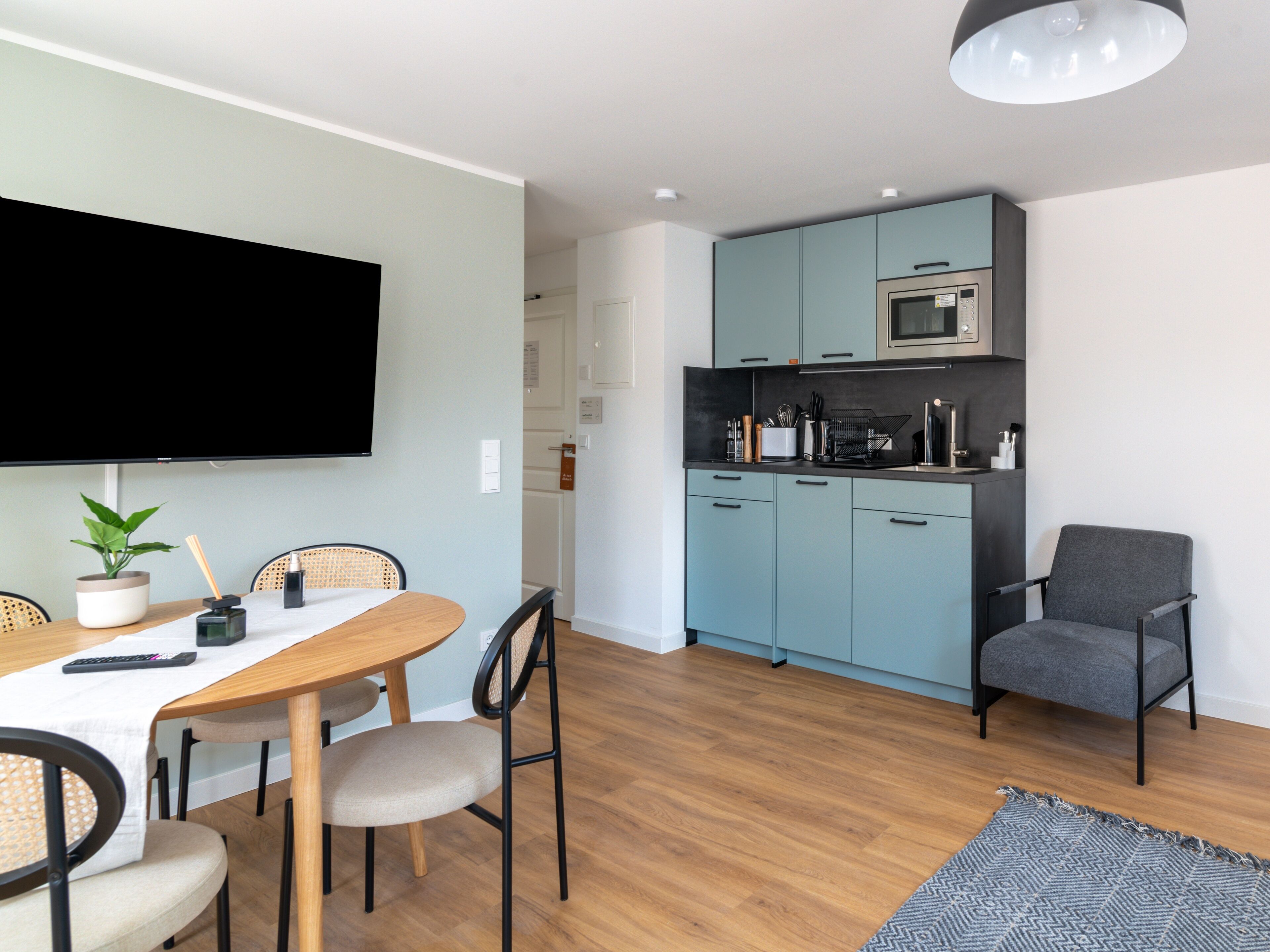 A compact living space with a dining area, kitchenette, and a gray armchair.