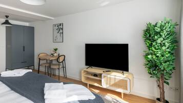 Um quarto moderno com uma cama, uma escrivaninha, uma televisão e um vaso de planta.