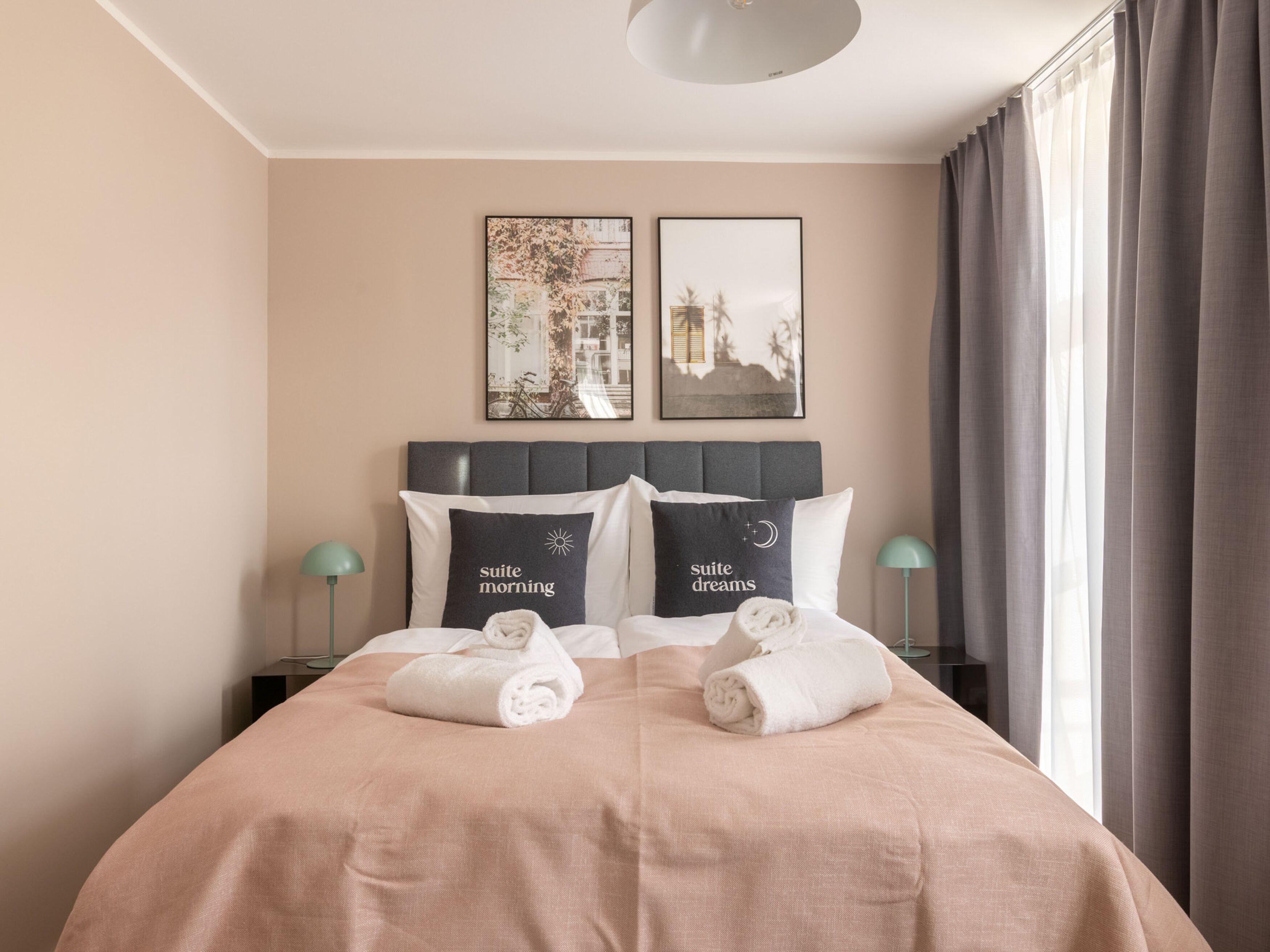 A neatly made bed with two pillows, a headboard, and two bedside tables with lamps.