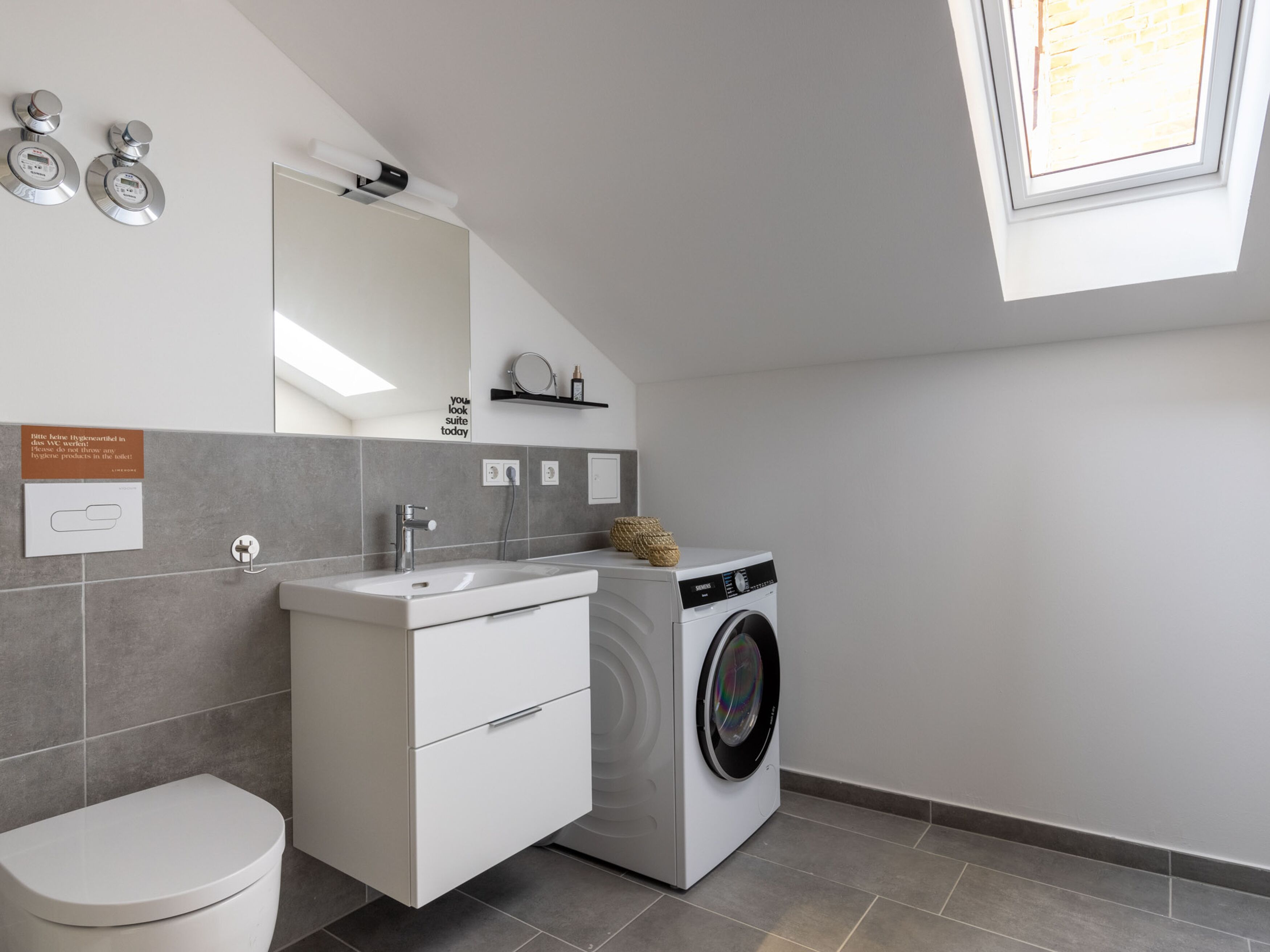 Un baño moderno con inodoro, lavamanos y lavadora.
