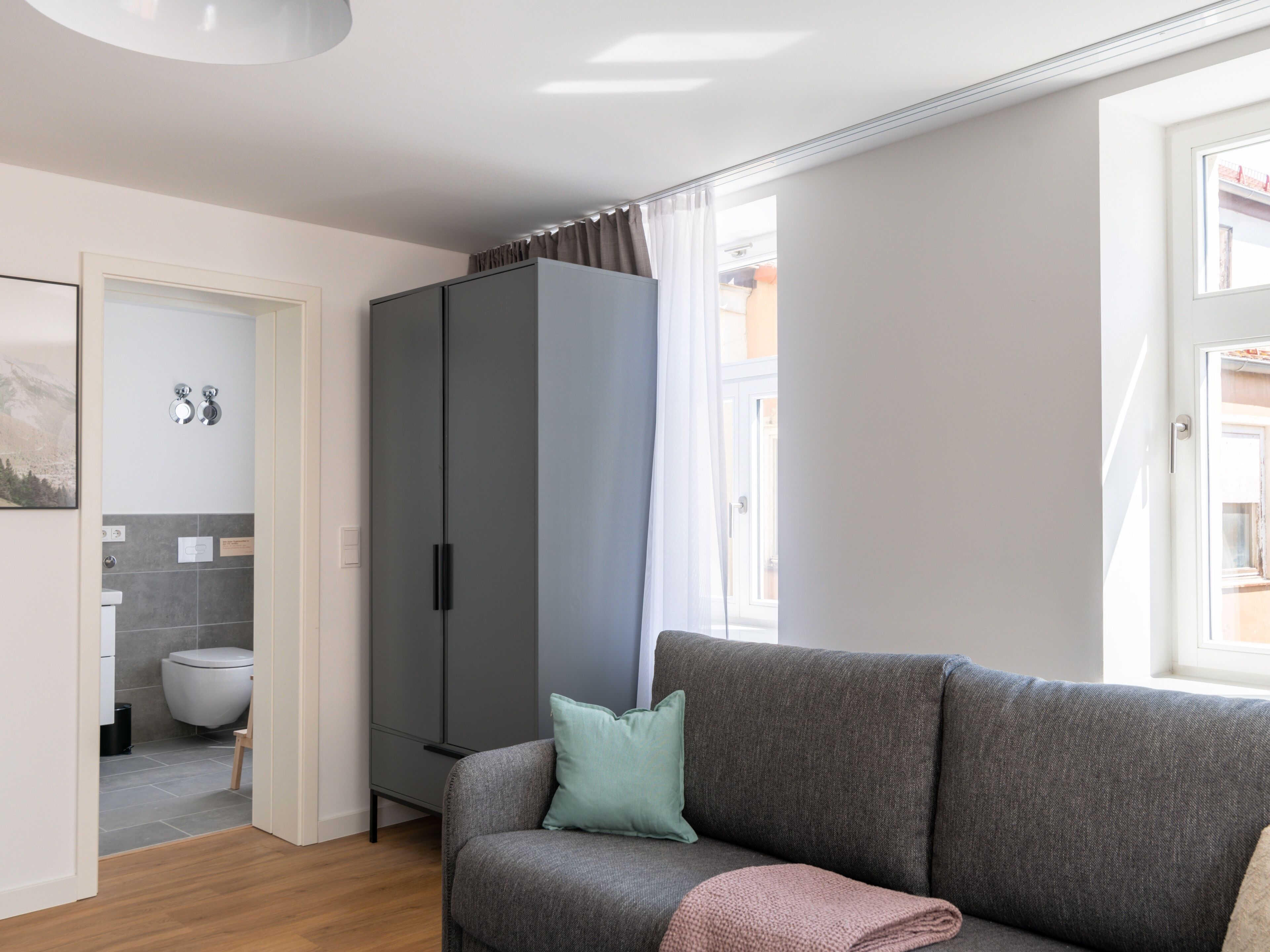 A modern living room with a grey sofa, a cabinet, and a view of the outside.