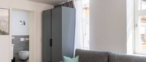 A modern living room with a grey sofa, a cabinet, and a view of the outside.