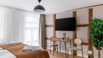 Une chambre d’hôtel moderne équipée d’un lit, d’un bureau, de deux chaises, d’une télévision et d’une plante en pot.