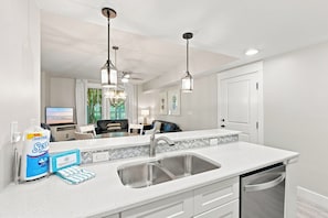 A modern kitchen with a stainless steel sink, white cabinetry, and pendant lighting.