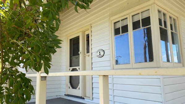 A white building with a porch, a door, and a window with a sign that reads "Dowling Street."
