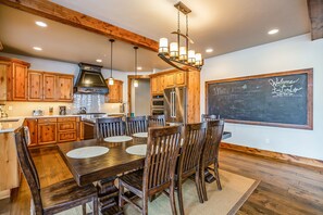 Une cuisine spacieuse avec des meubles en bois, un grand îlot central et un mur recouvert d’un tableau noir.