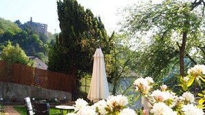Un giardino con fiori bianchi, un recinto di legno e un tavolo con sedie.