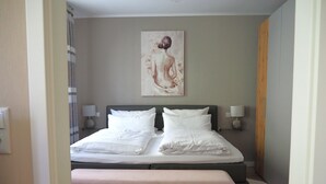 Un letto rifatto con lenzuola bianche, una testiera e due lampade ai lati.