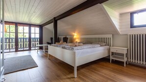 A bedroom with a sloped ceiling, a bed with pillows and a blanket, a bedside table, and a radiator. - Haus mitten in den Weinbergen - Haus 44. Frühstücksservice möglich! (Liběšice)