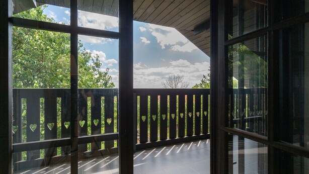 A covered outdoor area with a wooden deck and a view of trees and sky through large windows. - Haus mitten in den Weinbergen - Haus 44. Frühstücksservice möglich! (Liběšice)