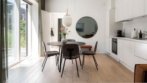 A modern kitchen with white cabinets, a round mirror, and a dining area with a round table and chairs.