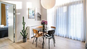 Un coin repas moderne avec une table ronde, quatre chaises, une plante en pot (un cactus) et un luminaire suspendu.