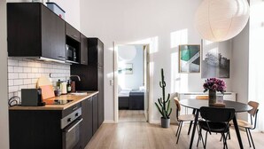Une cuisine moderne avec des meubles de couleur sombre, un four encastré et un coin repas comprenant une table ronde et des chaises.