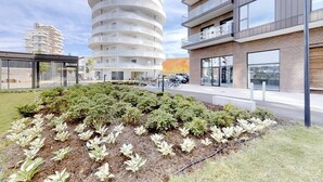 Un bâtiment moderne à la conception circulaire, un jardin aménagé avec différentes espèces de plantes et un espace de stationnement équipé de supports à vélos.