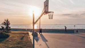 Un panier de basket au bord de l’eau, au coucher du soleil.